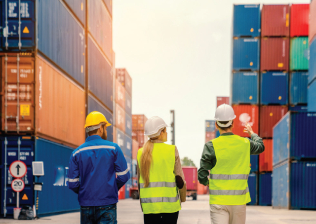 Three people moving through a container yard at a port