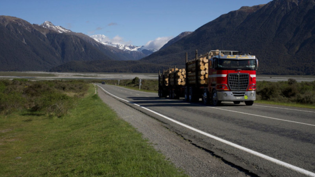 Logging truck driving through a scenic South Island mountain landscape.