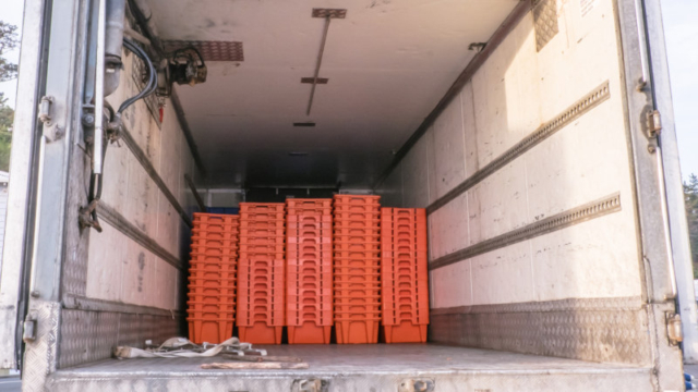 Stack of empty crates in the back of a large freight truck.